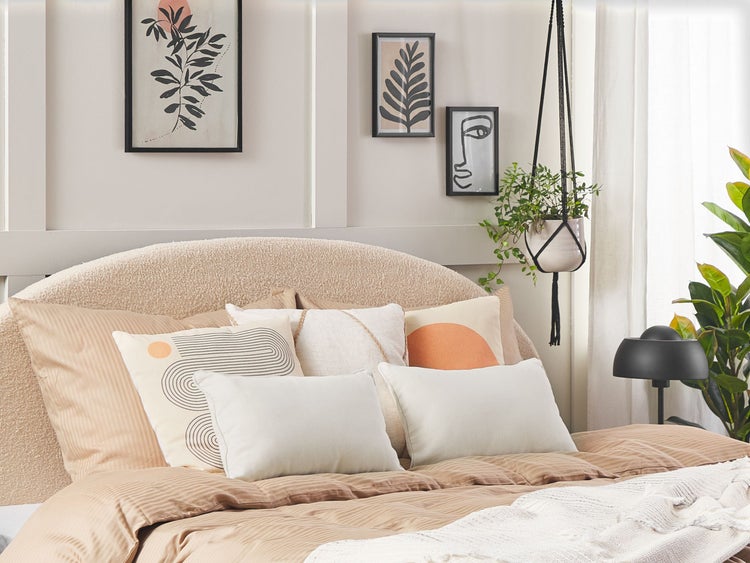 Schlafzimmer mit Bett, Kissen, Bildern und Hängepflanze