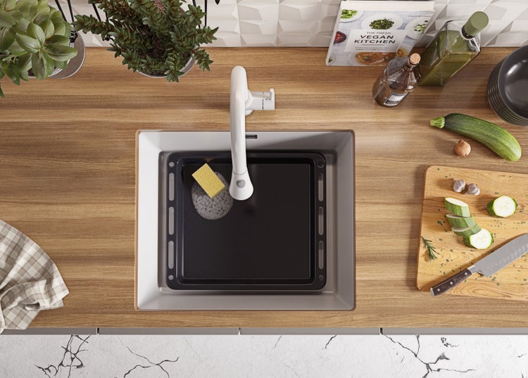 Küchenszene mit Spüle, Abtropfschale, Spültuch, Gemüse und Kochbuch auf einer Arbeitsplatte