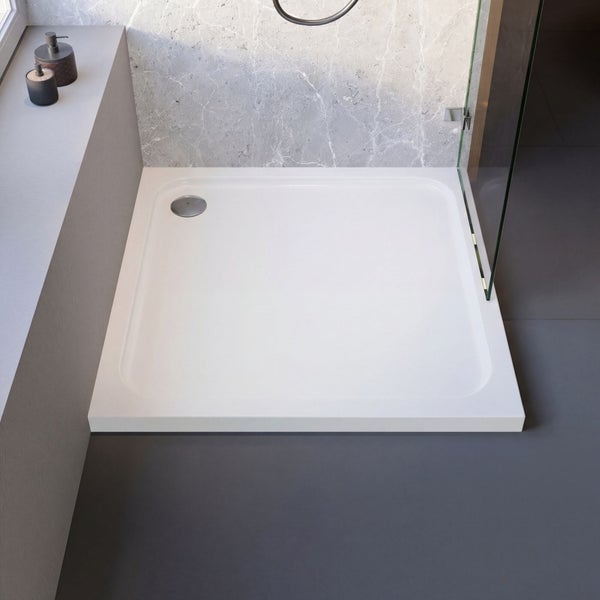 Quadratische weiße Duschwanne mit rundem Eckablauf in einem modernen, hellen Badezimmer mit Marmorwand und gläserner Duschwand.