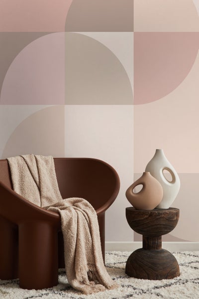 Dekorative Szene mit Sessel, Decke, Beistelltisch und Vasen vor einer geometrischen Wand