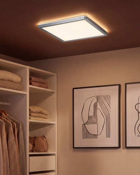 Quadratische LED Deckenleuchte in moderner Optik zur Beleuchtung eines begehbaren Kleiderschranks mit Regalen und Wandbildern.