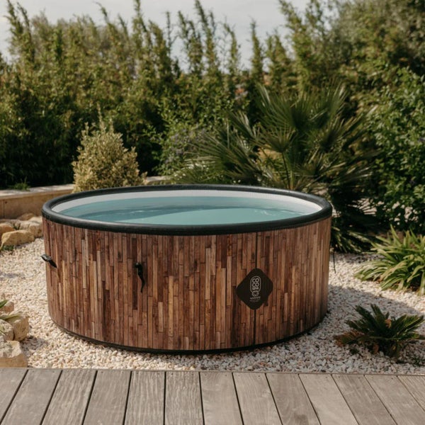Runder aufblasbarer Whirlpool in Holzoptik im Garten auf hellem Kies neben einer Holzterrasse.
