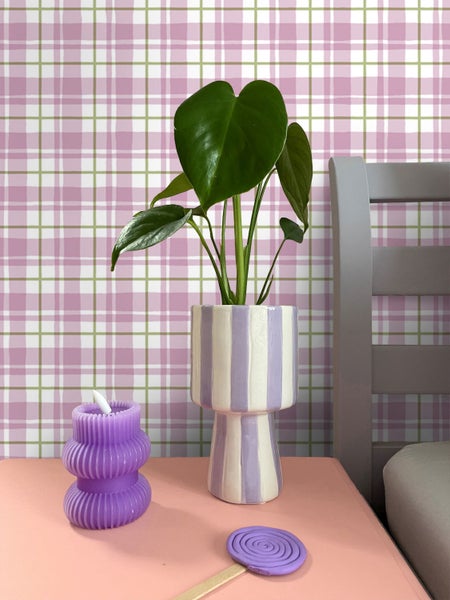 Dekorative Szene mit Zimmerpflanze in gestreiftem Topf, gewundener Kerze und Lolli auf einem Tisch
