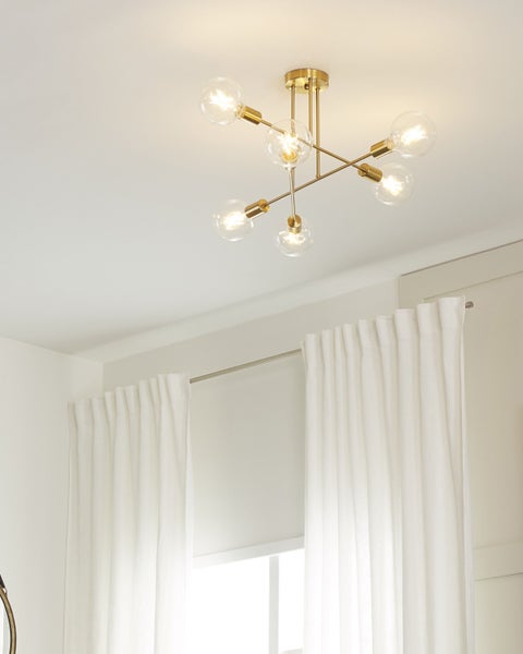 Moderne Deckenleuchte aus Metall in Messing-Optik mit sechs transparenten Globe-Leuchtmitteln an horizontalen Armen.