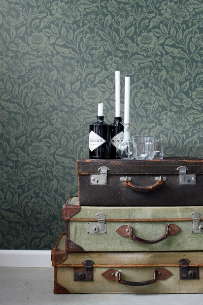 Dekorative Szene mit Vintage-Tapete, gestapelten Koffern und Accessoires