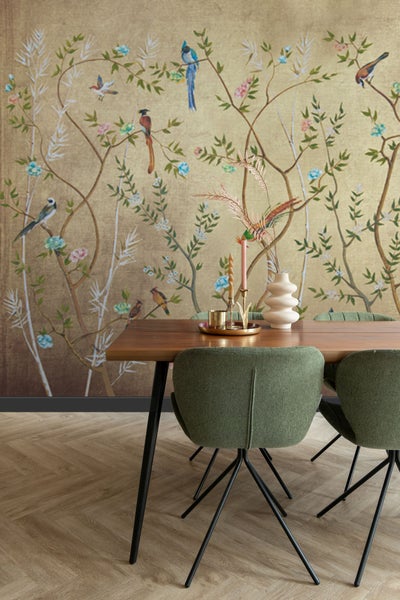 Esstisch mit Dekoration vor einer Wand mit Vogelmuster-Tapete.