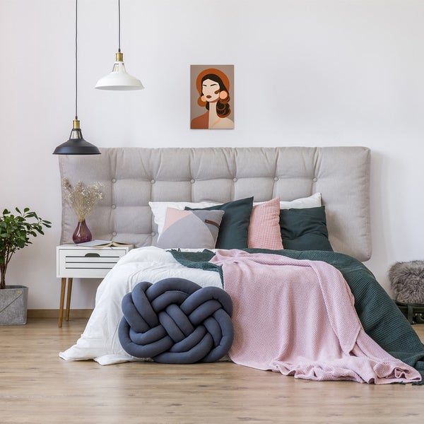 Schlafzimmer mit Bett, Nachttisch, Zimmerpflanze und Dekorationen