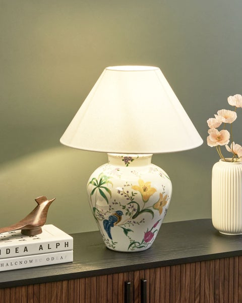 Dekorative Tischleuchte mit floralem Muster und Lampenschirm auf einem Nachttisch