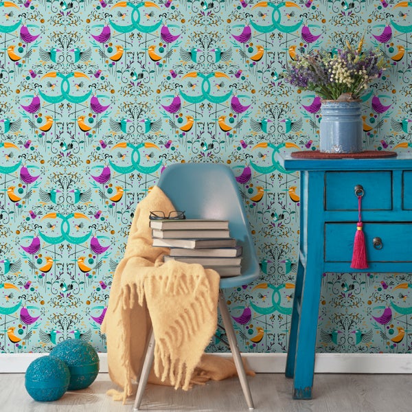 Dekoratives Zimmer mit einer Wandtapete mit Vogelmuster, einem blauen Beistelltisch mit Blumen und einem Stuhl mit einer Decke und Büchern.