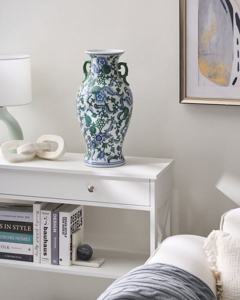 Dekoratives Arrangement mit einer verzierten Vase auf einem weißen Konsolentisch.