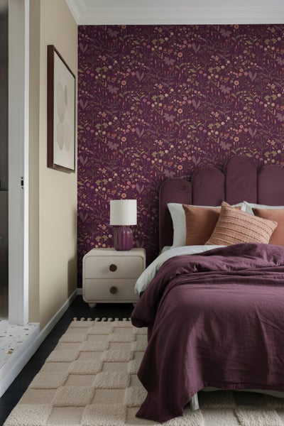 Schlafzimmer mit gemusterter Tapete, Bett, Nachttisch und Teppich