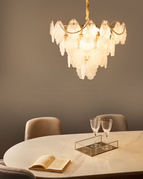 Dekorative Hängeleuchte über einem Esstisch mit Buch und Gläsern, schafft eine helle und einladende Atmosphäre