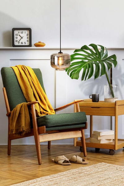 Innenaufnahme eines Zimmers mit Sessel, Beistelltisch, Pendelleuchte und Dekorationsgegenständen