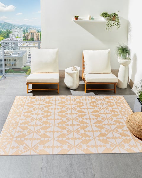 Heller Balkon mit Outdoorteppich mit geometrischem Muster, Holzsesseln mit weißen Polstern und Beistelltisch auf Fliesenboden.