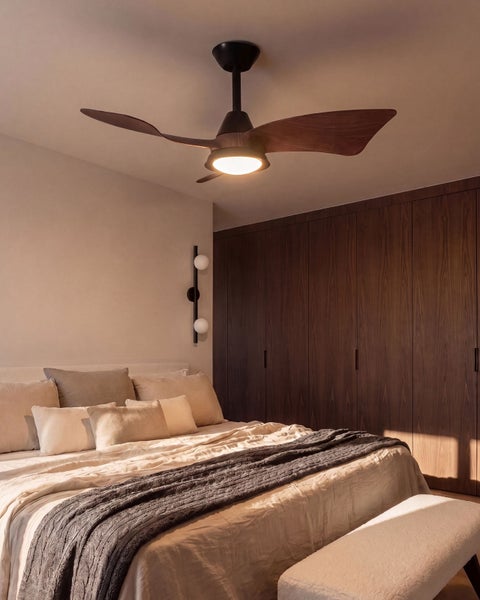 Moderner Deckenventilator mit Beleuchtung und geschwungenen Holzflügeln in einem stilvoll eingerichteten Schlafzimmer mit großem Einbauschrank.