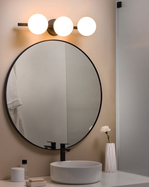 Badezimmer mit rundem Spiegel, Aufsatzwaschbecken und Wandleuchte