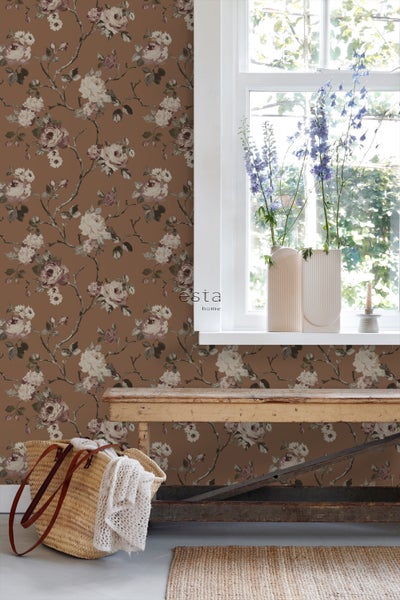 Dekoratives Zimmer mit Esta Home Tapete mit Blumenmuster, Fenster und Holztisch.