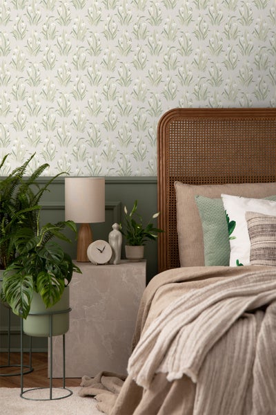 Dekoratives Schlafzimmer mit floral gemusterter Tapete und Beistelltisch