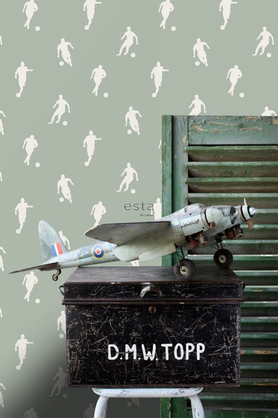 Dekorative Szene mit Flugzeugmodell auf Kiste und Tapete mit Fußballmotiven