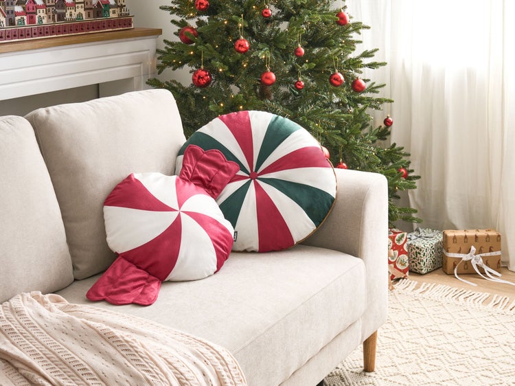 Festliche Wohnzimmerszene mit Sofa, Weihnachtsbaum und dekorativen Süssigkeitenkissen