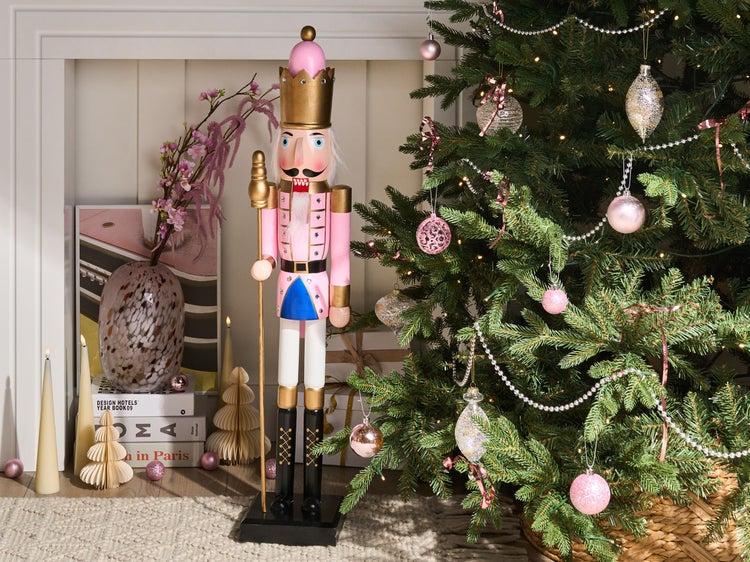 Dekorative Weihnachtsszene mit Nussknackerfigur und geschmücktem Weihnachtsbaum.