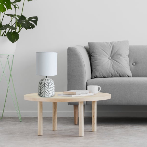 Wohnzimmerszene mit Tischleuchte, Couch, Zimmerpflanze und Beistelltisch