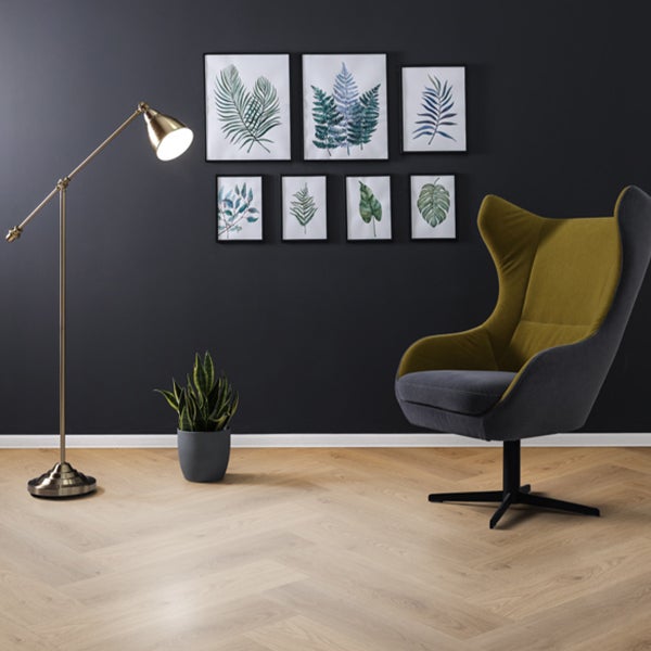 Wohnzimmer mit Stehlampe, Sessel und Pflanzenbildern an der Wand