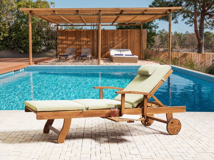 Szene mit einem Holzpoolliegenstuhl neben einem Poolbereich mit Gartenmöbeln unter einer Holzpergola