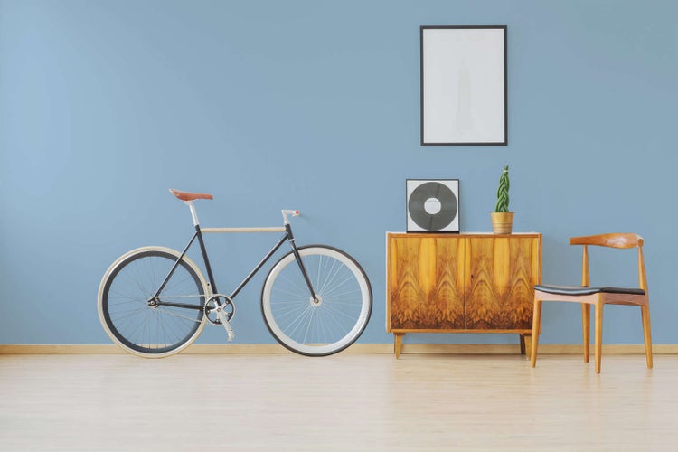 Helles Zimmer mit Holzfußboden, Fahrrad, Sideboard aus Holz und einem Holzstuhl.