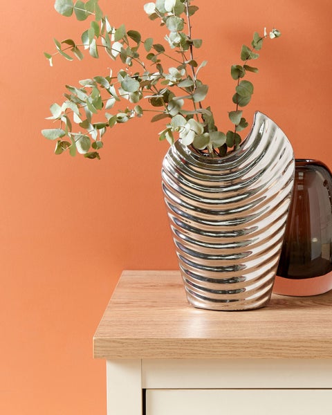 Dekorative silberfarbene Vase mit Eukalyptus auf einem Tisch