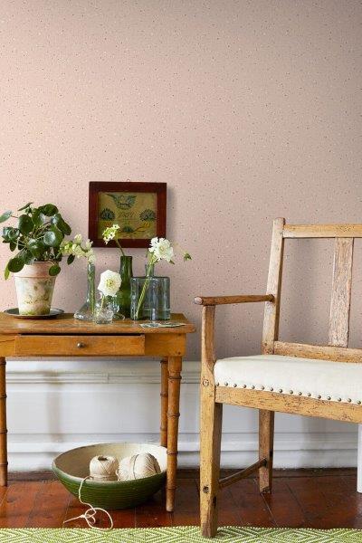 Raumansicht mit Tür, Stuhl mit Hut und Kommode mit Dekoration