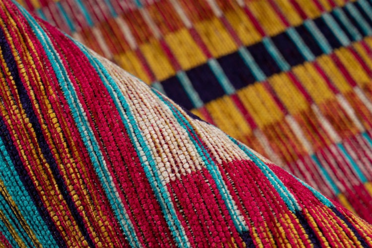 Nahaufnahme eines gewebten Teppichs mit buntem Streifenmuster, die Oberflächenstruktur und Garnstruktur zeigt.