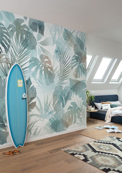 Helles Schlafzimmer mit Wandtapete mit tropischen Blättern, Surfbrett und Teppich