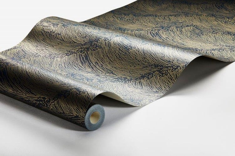 Ein Schlafzimmer mit gemusterter Tapete, Bett und einem Hocker mit einem Tuch.