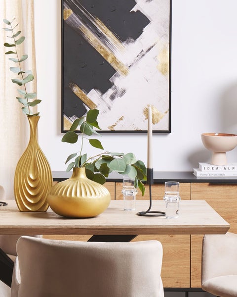 Tischdekoration mit goldenen Vasen, Kerzenständer, Trinkgläsern und abstraktem Gemälde