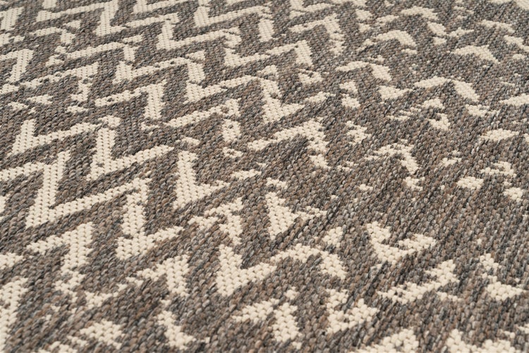 Nahaufnahme eines gewebten Teppichs mit grafischem Zickzackmuster und strukturierter Oberfläche.