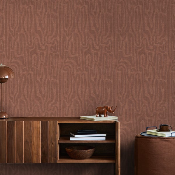 Vliestapete mit organischem Wellenmuster in Braun hinter einem Sideboard aus Holz in einem modern eingerichteten Wohnzimmer.