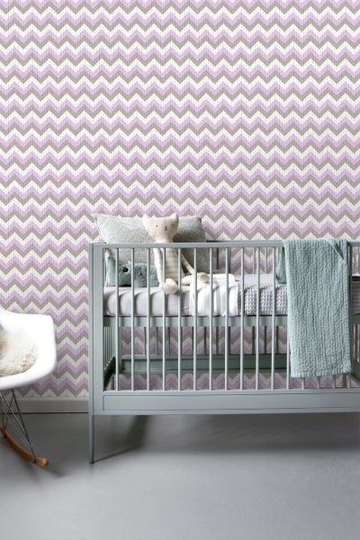 Kinderzimmer mit Wandtapete im Zickzackmuster, Babybett und Schaukelstuhl