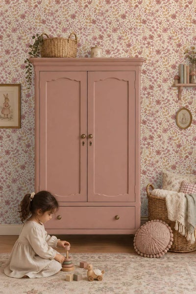 Wohnraum mit floraler Mustertapete über einem halbhohen Wandpaneel, kombiniert mit einer Kommode und einem Schaukelstuhl im Kinderzimmer.