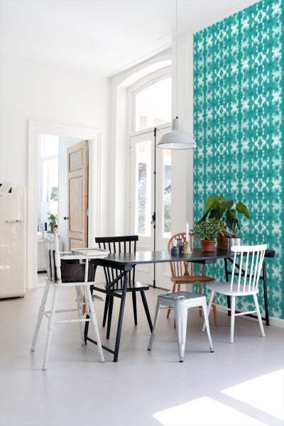 Esszimmer mit Esstisch und Stühlen vor einer gemusterten Tapete
