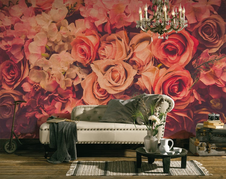 Innenraum mit Fototapete mit großen Rosen, einer hellen Polsterliege, Vintage-Koffern und einem Kristallkronleuchter.