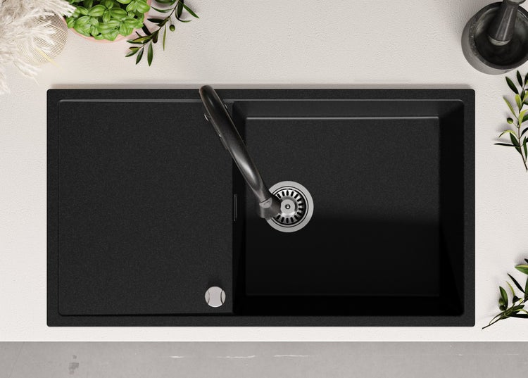Schwarze Küchenspüle mit Abtropffläche und Wasserhahn von oben