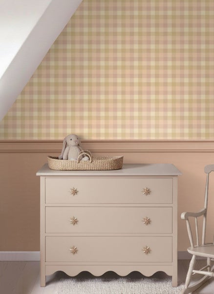 Helles Kinderzimmer mit karierter Tapete, Kommode aus Holz mit drei Schubladen, Wandleiste und einem Stoffhasen in einem geflochtenen Korb.