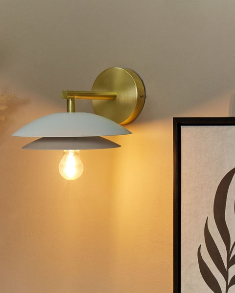 Moderne Wandleuchte mit Messinghalterung und gestuften Schirmen, an einer Wand montiert und eingeschaltet.