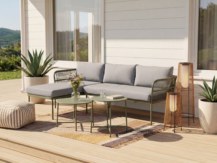 Moderne Outdoor-Lounge auf einer Holzterrasse mit L-Sofa, zwei runden Beistelltischen, Outdoorteppich, Laternen und Topfpflanzen.