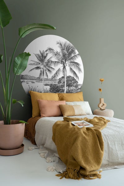 Schlafzimmer mit Bett, Kissen, Tagesdecke und Wandbild mit Palmenmotiv