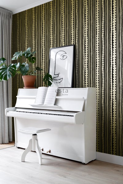 Wohnraum mit gemusterter Tapete, weißem Klavier und Zimmerpflanze