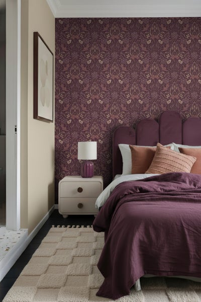 Schlafzimmer mit gemusterter Tapete, Bett, Nachttischlampe und Teppich