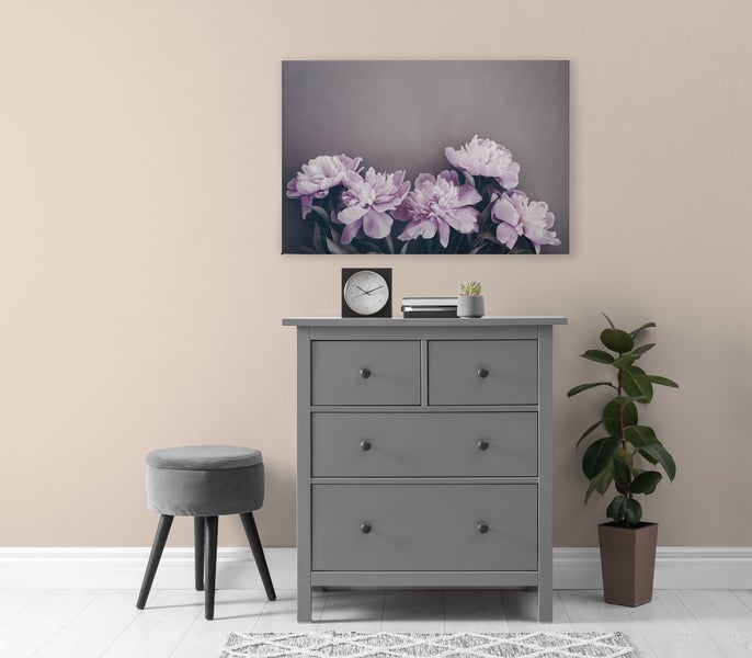 Wandbild mit Pfingstrosenmotiv über einer grauen Kommode in einem modern eingerichteten Wohnraum.