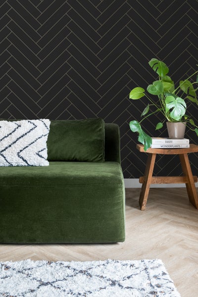 Wohnzimmer mit grüner Couch, Holzhocker und Tapete mit Fischgrätmuster